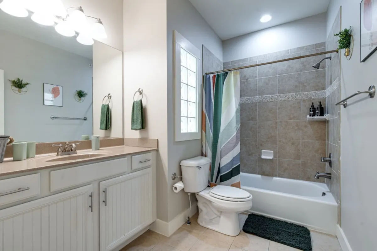 A bright, contemporary bathroom featuring a vanity with a modern sink, a glass-enclosed shower area, and thoughtful decorative touches on the wall. The space is designed to feel both fresh and calming, ideal for unwinding after a day or refreshing in the morning.