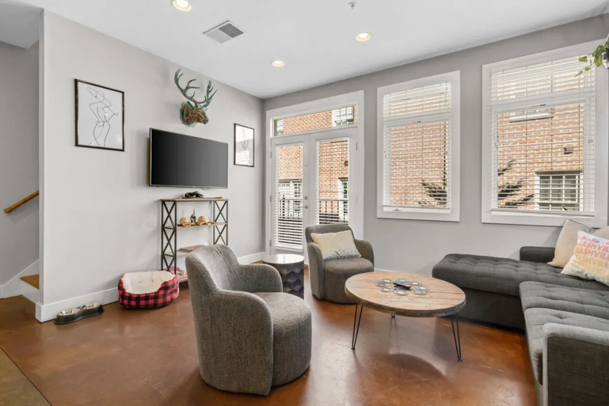 A cozy, contemporary living room featuring a comfortable sofa, a stylish coffee table, a smart television mounted on the wall, and large windows that flood the space with natural light. Modern artwork and thoughtful décor create an inviting atmosphere perfect for socializing, relaxing, or enjoying a movie night with friends or family.